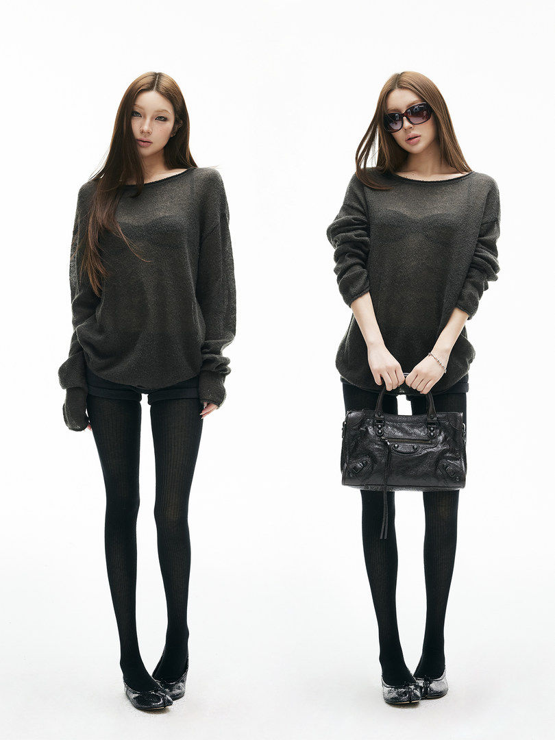 Model wearing an oversized dark knit sweater with black tights, sunglasses, and a handbag