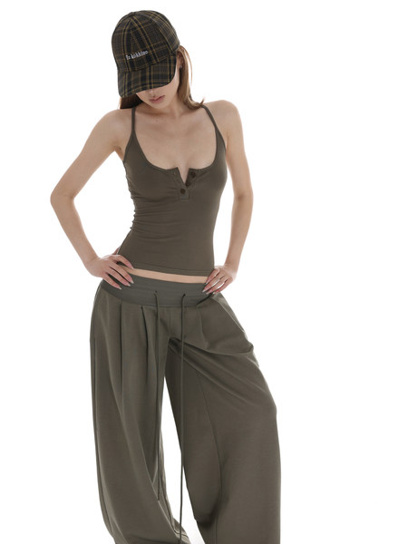 Model wearing an olive tank top, wide-leg pants, and a plaid cap