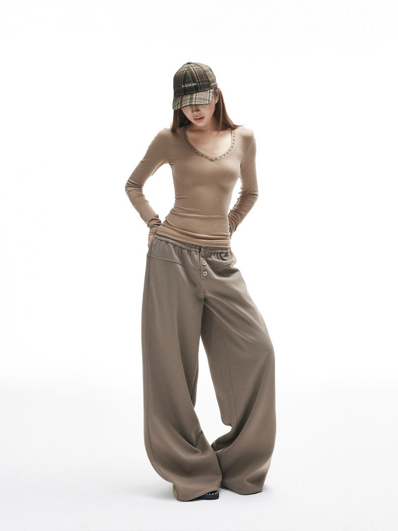 Model wearing a beige fitted long-sleeve top with oversized wide-leg pants and a plaid cap