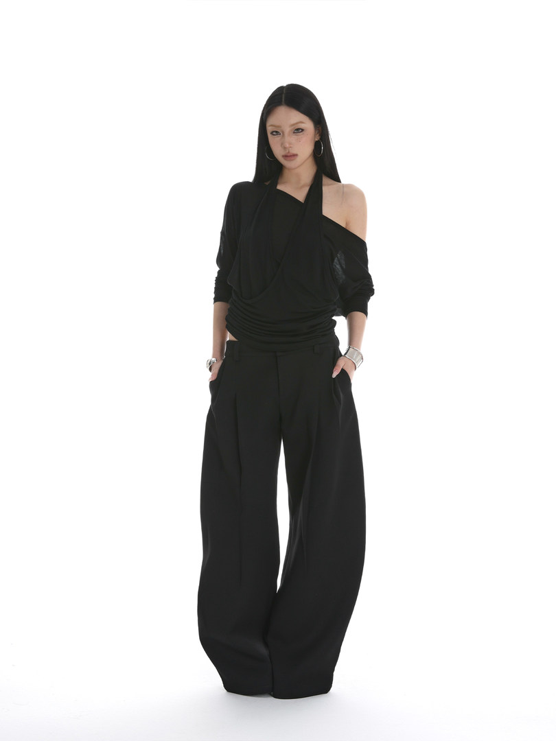 Black asymmetrical top with wide-leg pants worn by a model