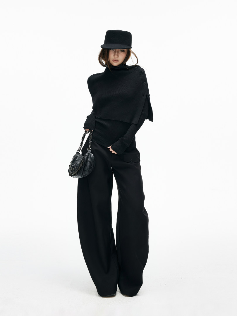 Model wearing an all-black fashion outfit with hat and chain bag