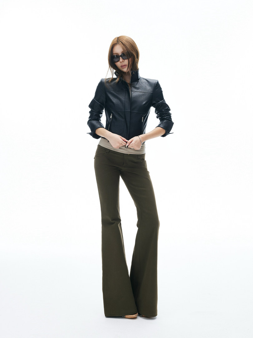 Model wearing a black leather jacket with dark flared pants on a white background