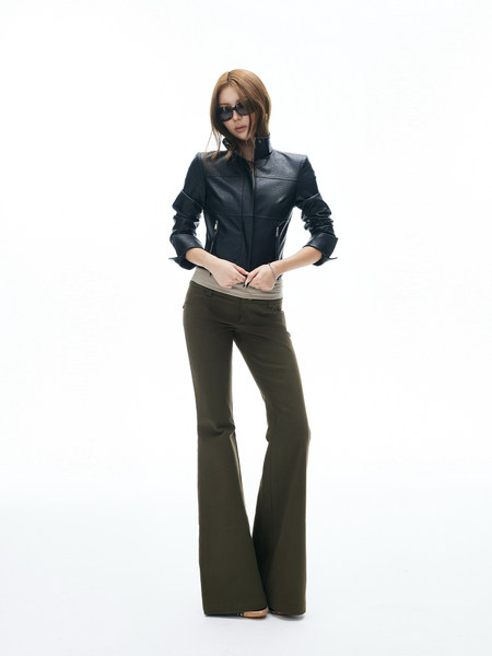 Model wearing a black leather jacket with dark flared pants on a white background