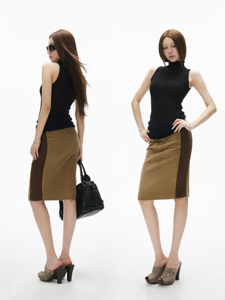 Model wearing a black sleeveless turtleneck with a tan-and-brown skirt and heels