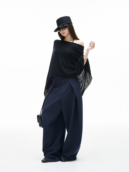 Model wearing a black off-shoulder top with wide-leg pinstripe pants and a hat