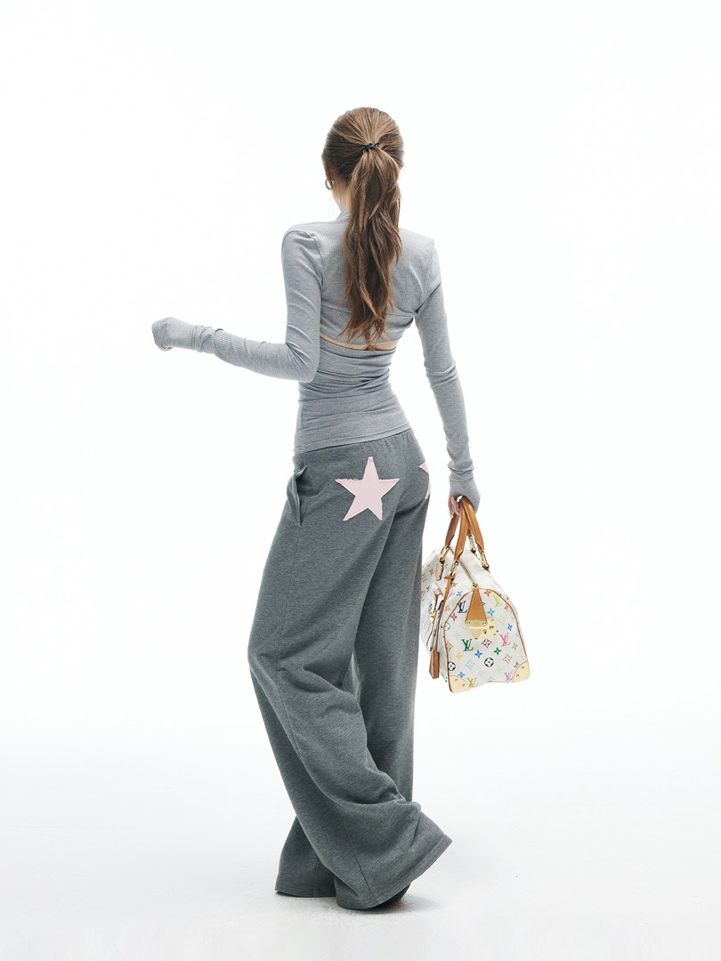 Woman wearing a gray loungewear set and holding a monogram handbag
