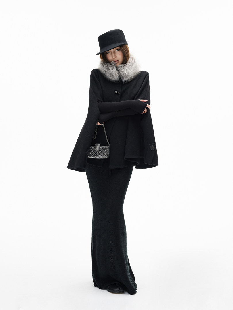 Black winter outfit on a model with a fur collar cape, cap, and long skirt