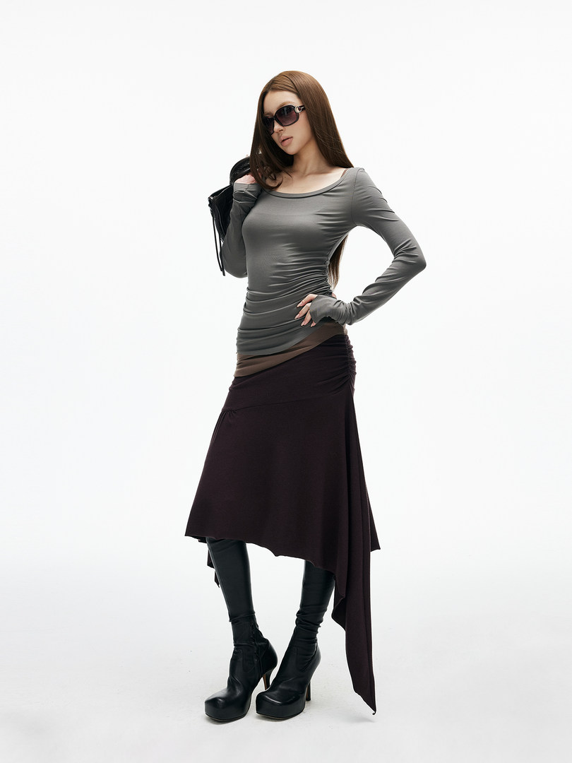 Model wearing a gray fitted long-sleeve top with a dark asymmetrical skirt and black platform boots