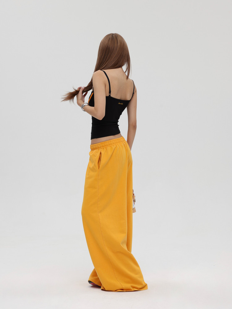 Model wearing a black camisole top with loose yellow wide-leg pants