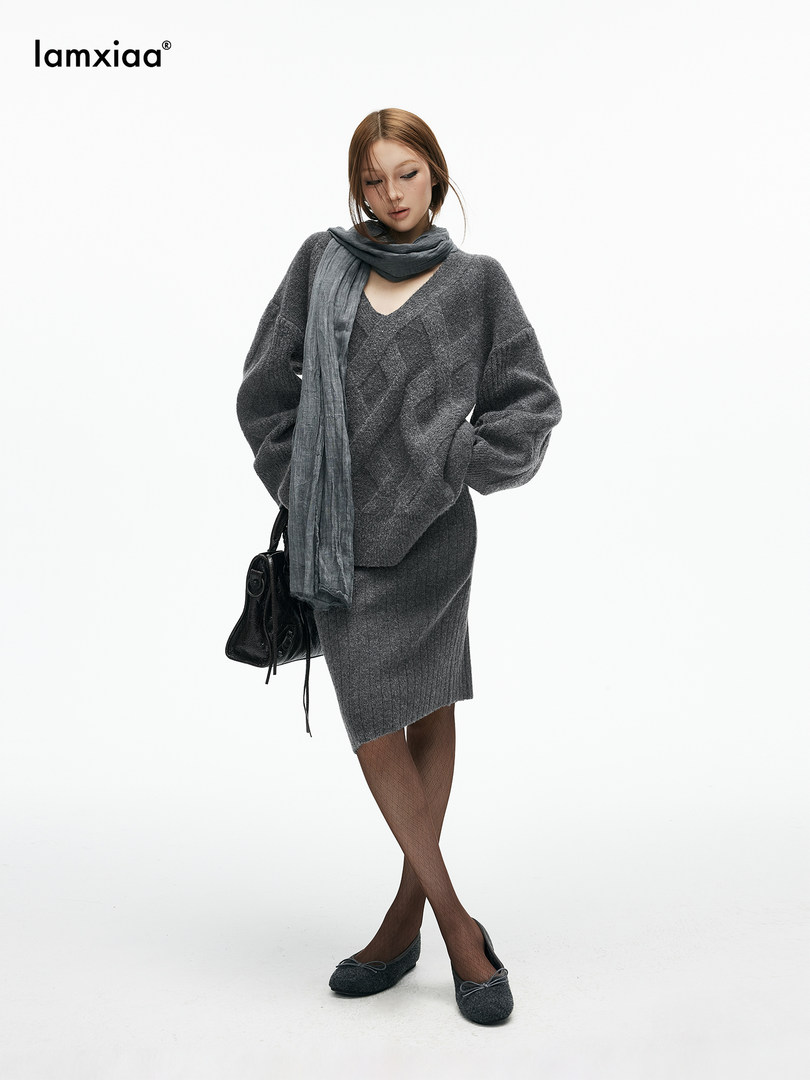 Model wearing a gray knit sweater and skirt set with scarf and handbag