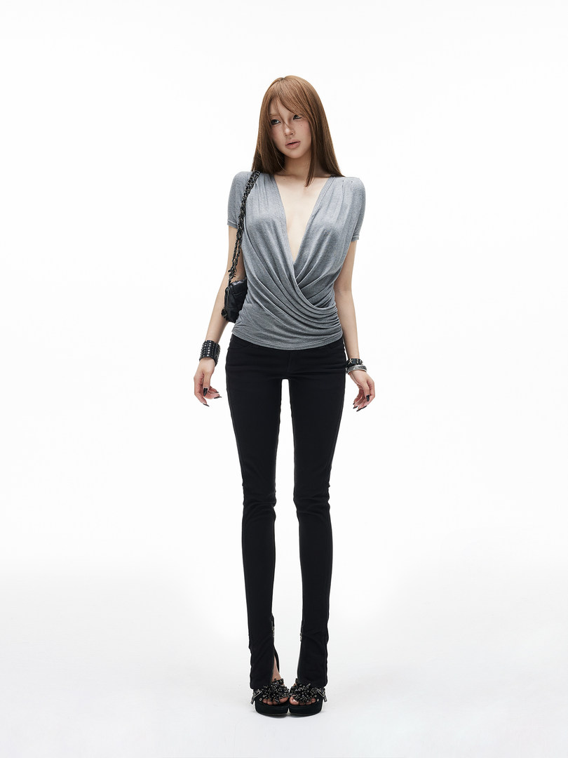 Model wearing a gray draped V-neck top with black skinny pants and platform sandals