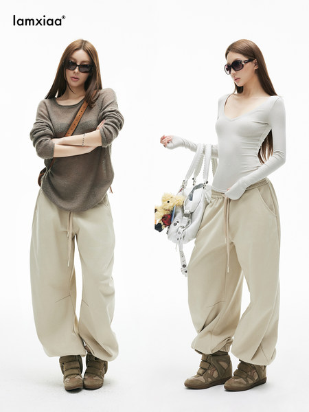 Two female models wearing beige wide-leg sweatpants with casual fitted tops and boots
