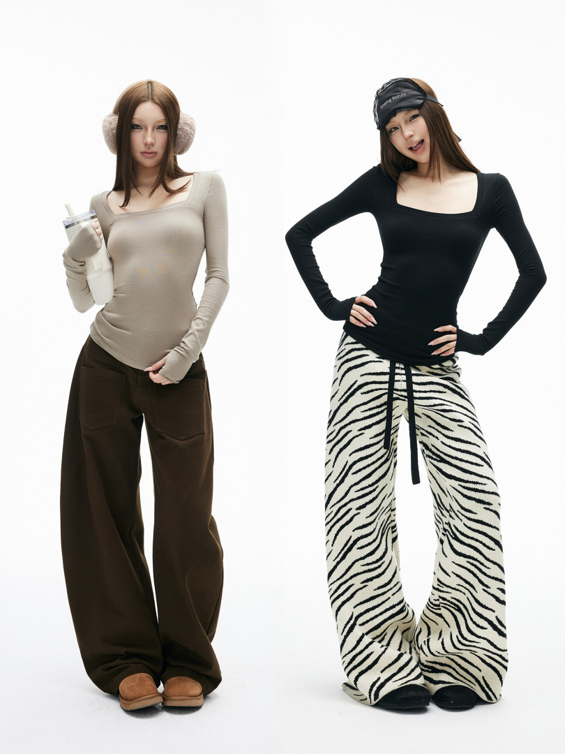 Two models wearing fitted long-sleeve tops and wide-leg pants in a fashion studio shot