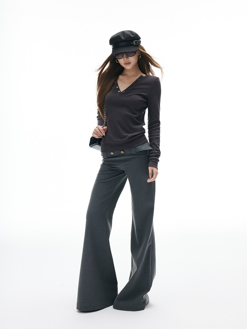Model wearing a dark long-sleeve top and wide-leg pants with a cap and sunglasses