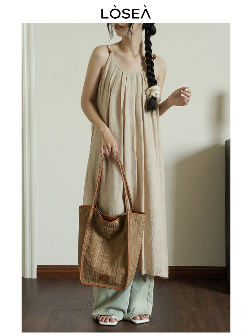 Beige sleeveless maxi dress worn by a model with a woven tote bag.