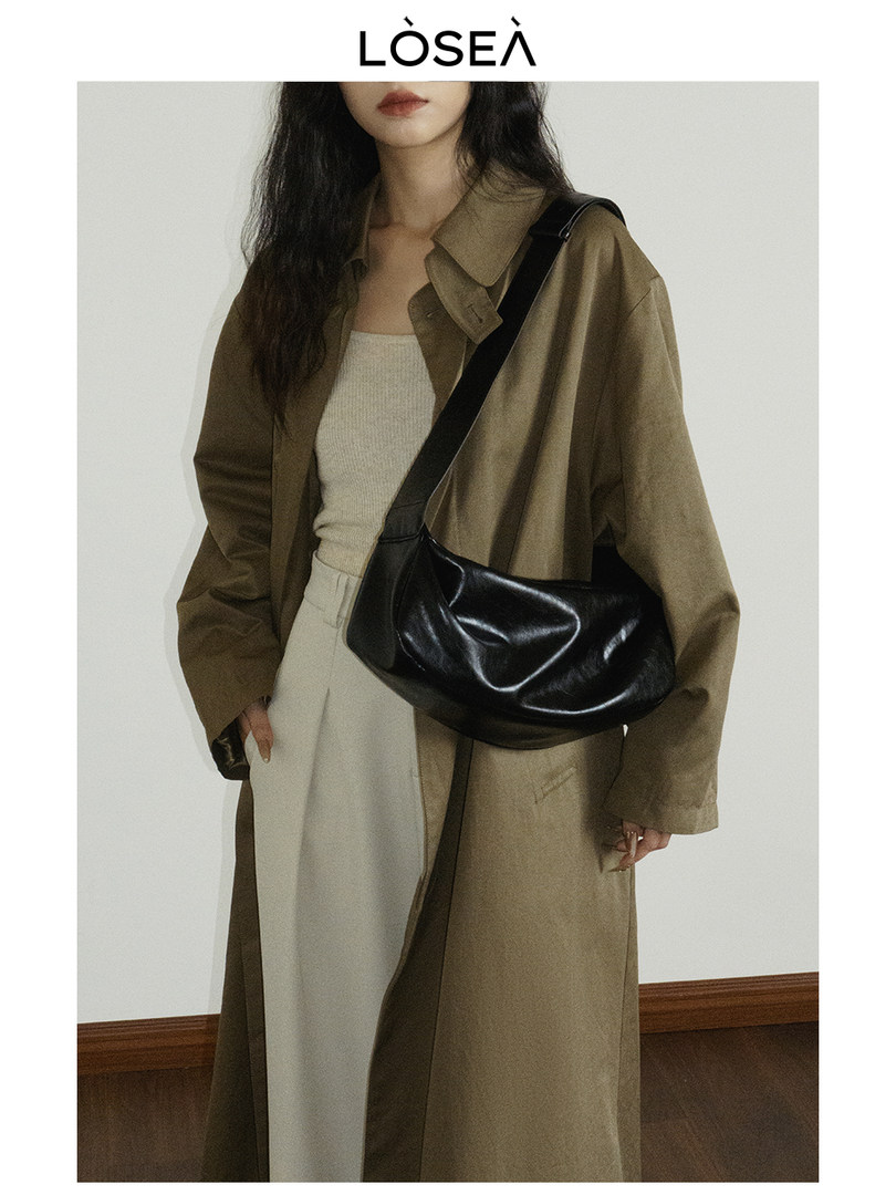 Model wearing a long brown trench coat with a black shoulder bag
