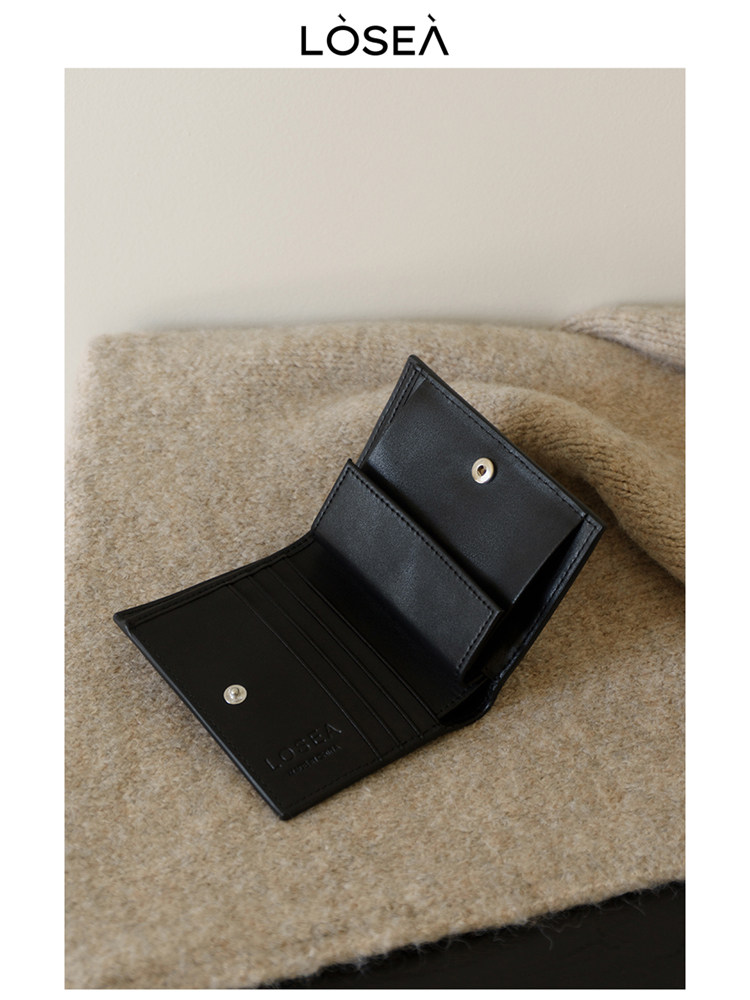 Black leather wallet or card holder open on a soft beige surface