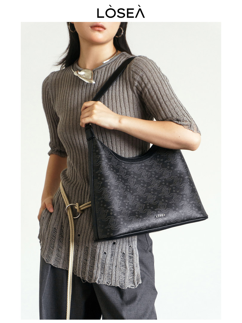 Model wearing a gray ribbed knit outfit and carrying a black shoulder bag
