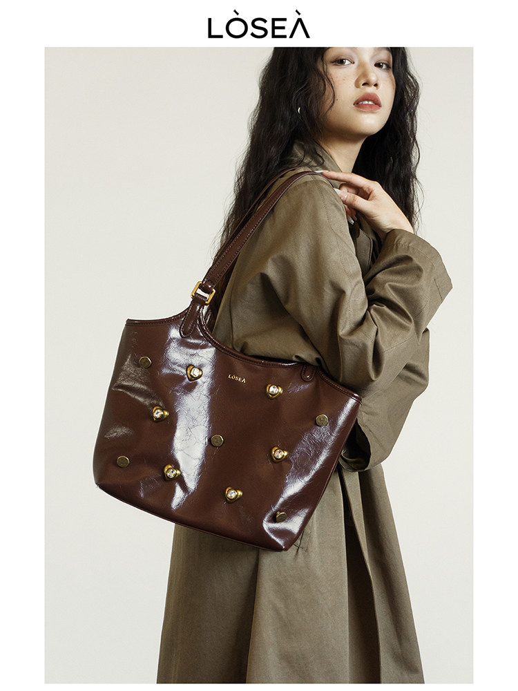Brown glossy studded handbag worn on a model