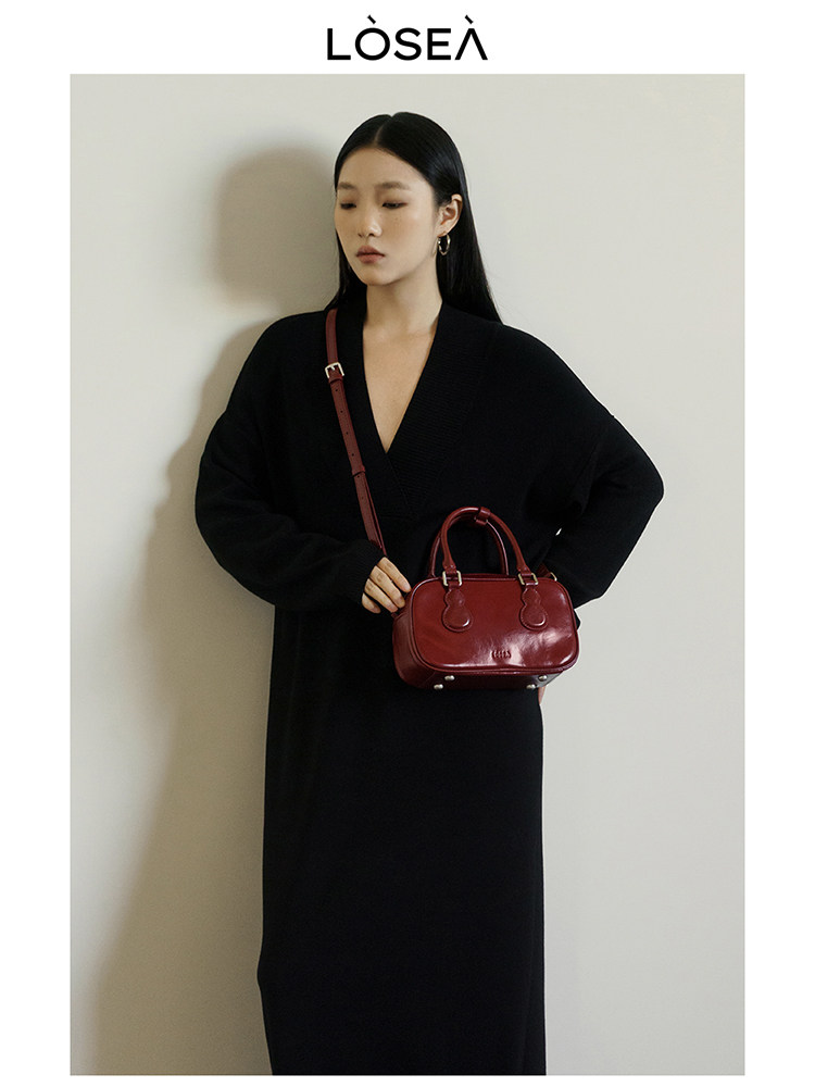 Woman in a black dress holding a red leather handbag