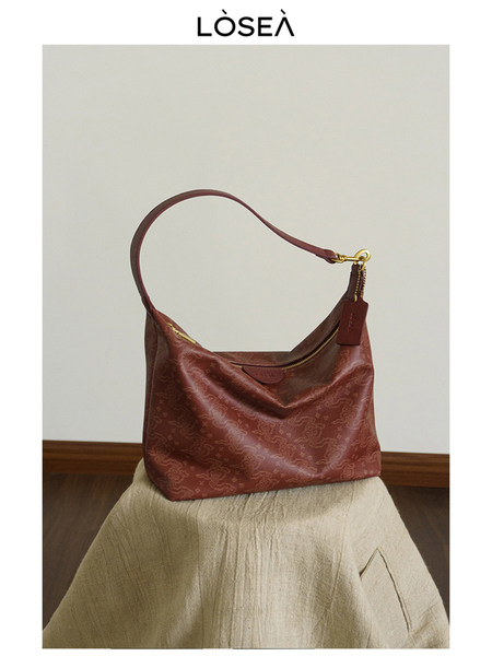 Red leather shoulder handbag with gold hardware on a neutral background