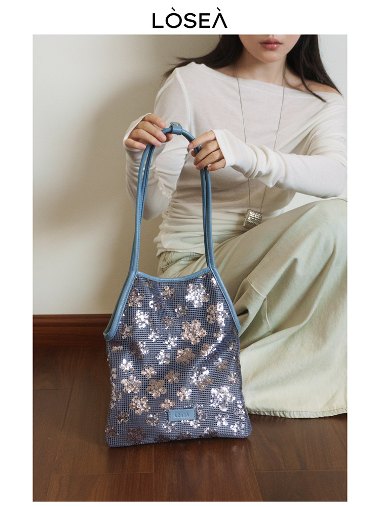 Blue floral sequin handbag held by a model