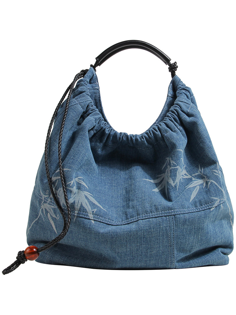 Blue denim hobo handbag with black handle and braided strap on white background