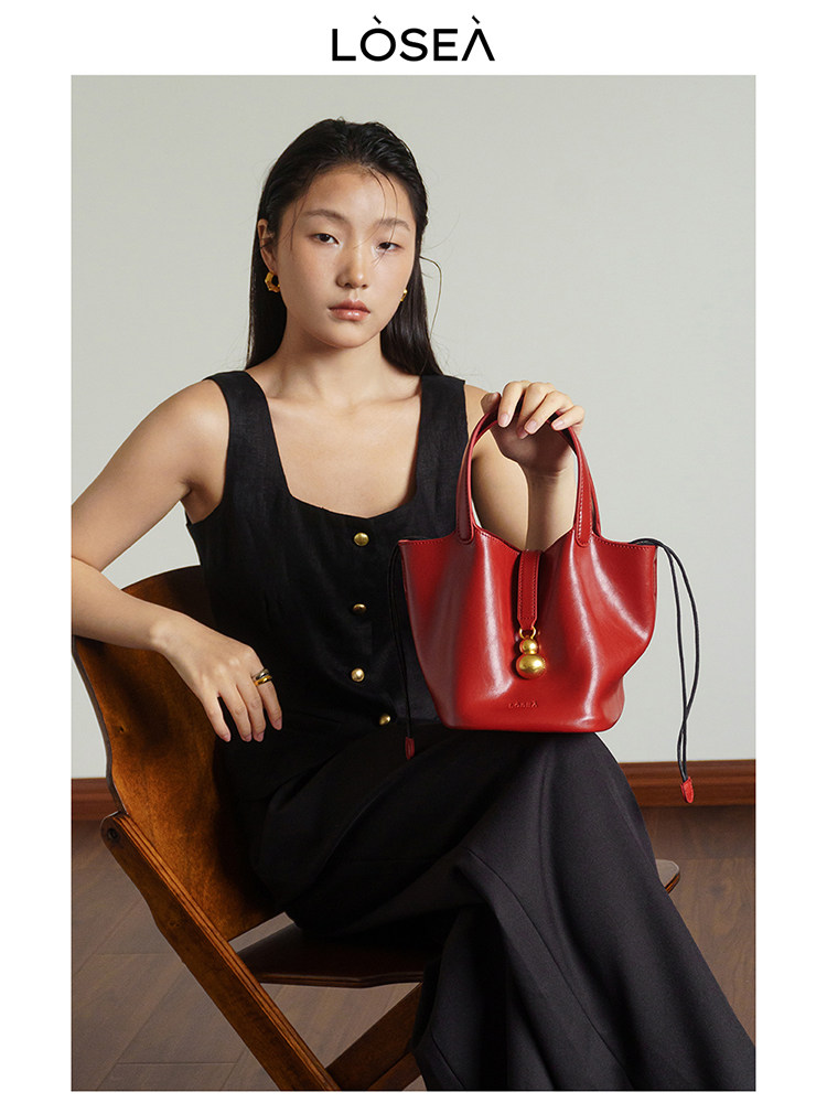 Woman holding a red leather handbag while wearing a black dress
