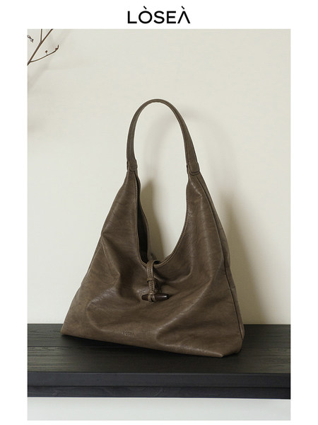 Brown leather slouchy tote handbag on a shelf