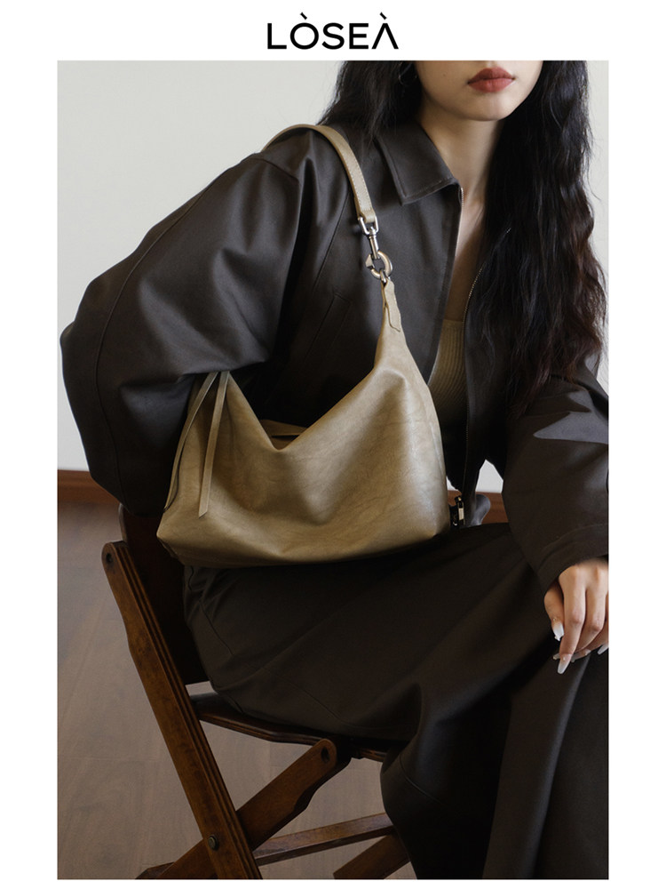 Beige shoulder handbag worn by a seated model