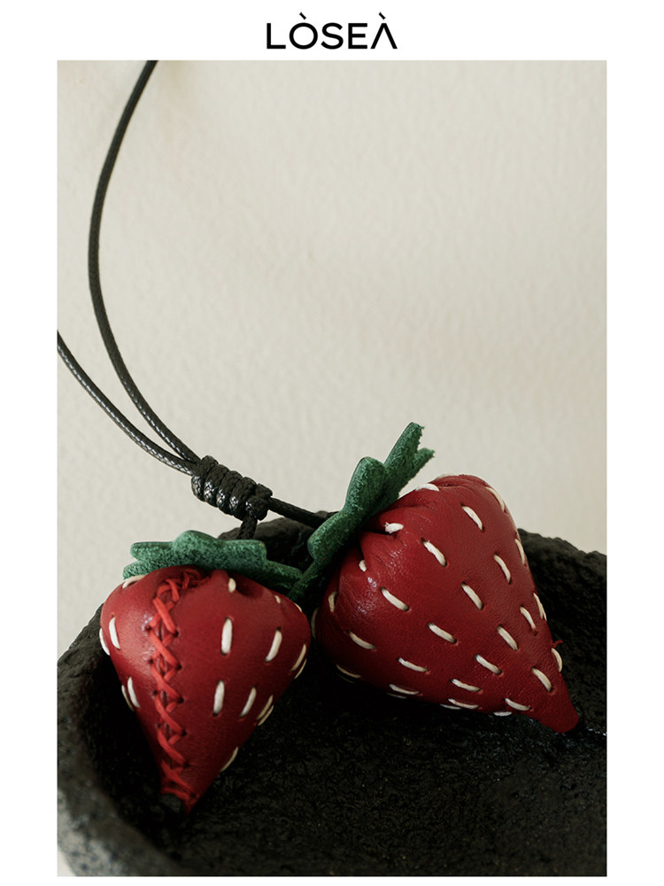 Strawberry-shaped pendant necklace on a black cord