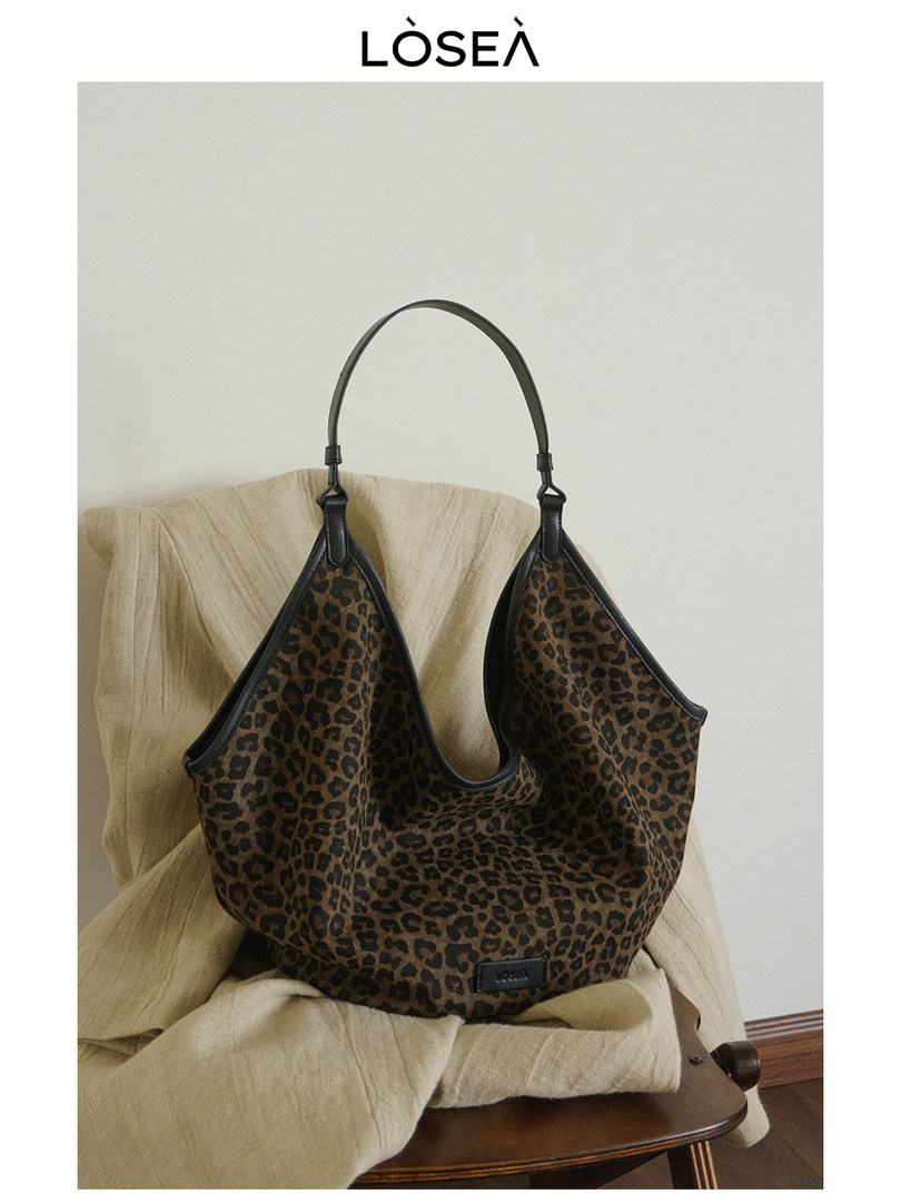 Leopard print shoulder handbag with black handles on a chair