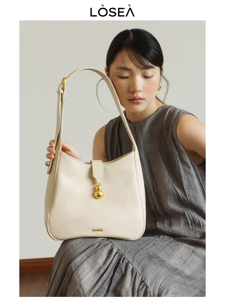 Cream leather shoulder handbag held by a model