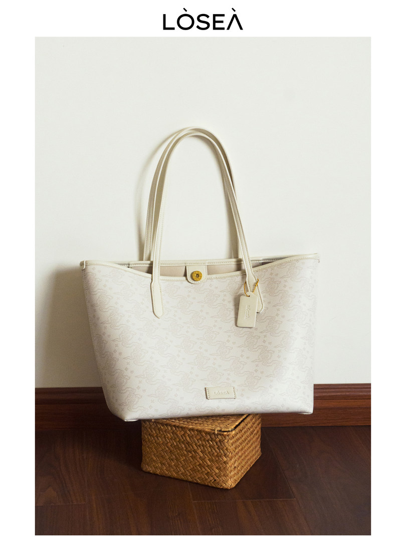Light beige tote handbag with long handles and a small hanging tag