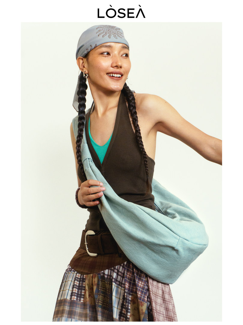 Model wearing a light blue shoulder bag and layered fashion outfit