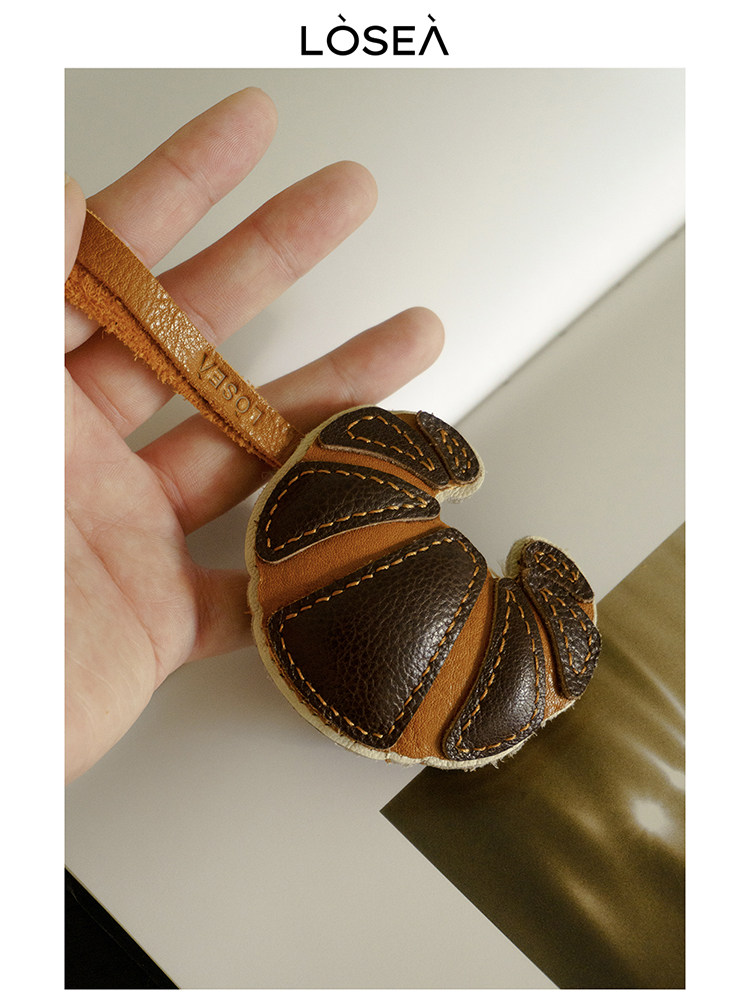 Small brown leather keychain accessory held in hand