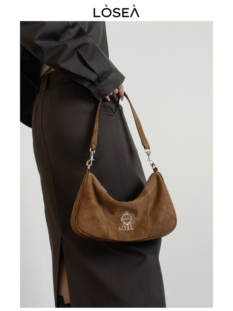 Brown suede shoulder bag worn by a model