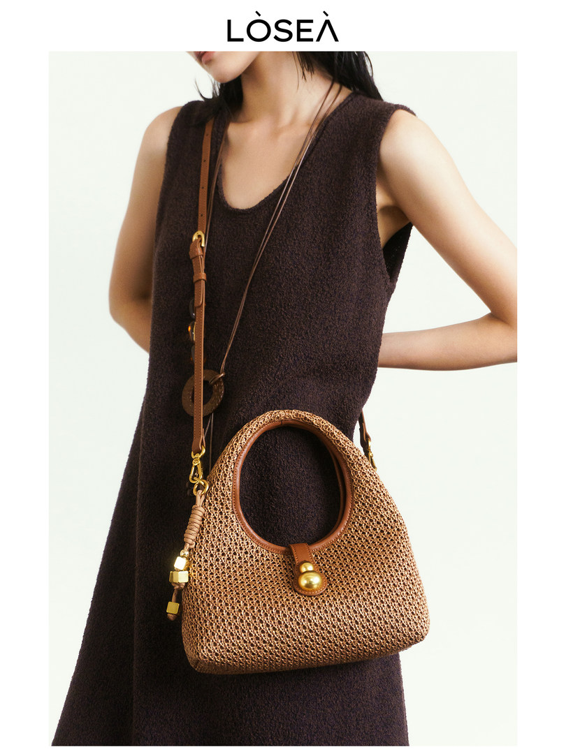 Model wearing a dark sleeveless dress with a woven tan handbag
