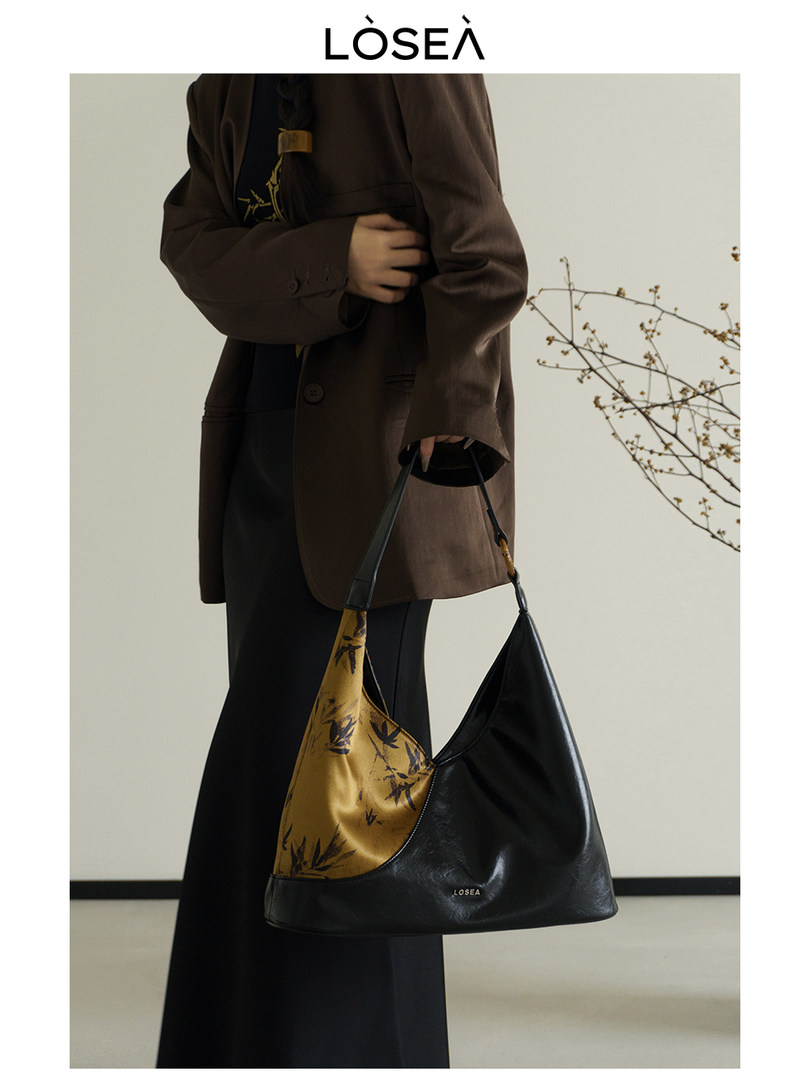 Black and mustard shoulder handbag worn by a model with a brown blazer