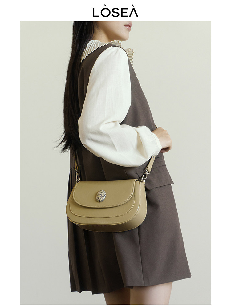 Beige shoulder handbag worn by a model with a brown outfit