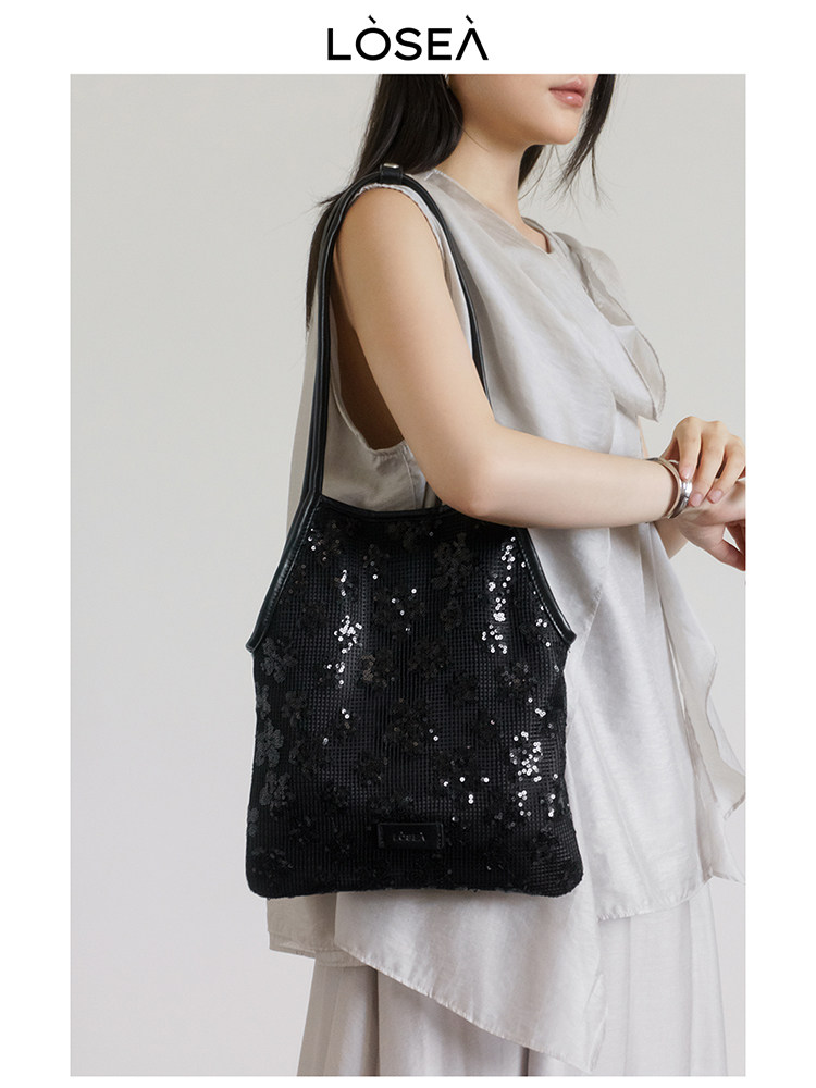 Black sequined shoulder bag worn by a model
