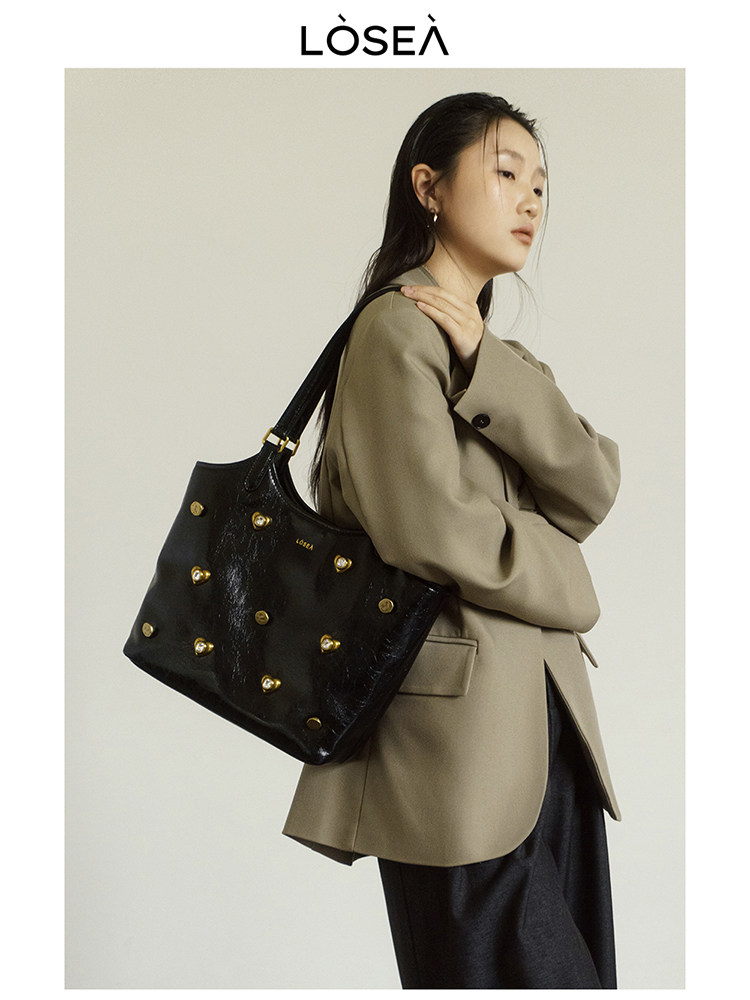 Black studded tote handbag worn by a model