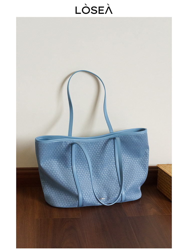 Blue textured tote bag with long handles on a floor display