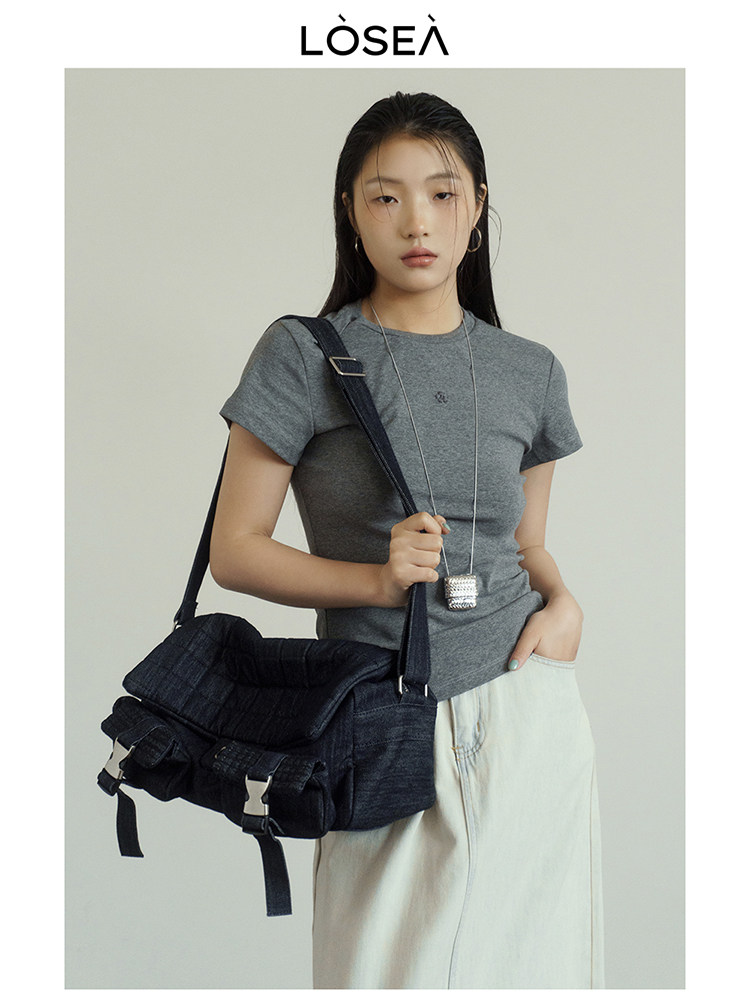 Model wearing a gray short-sleeve top with a black shoulder bag