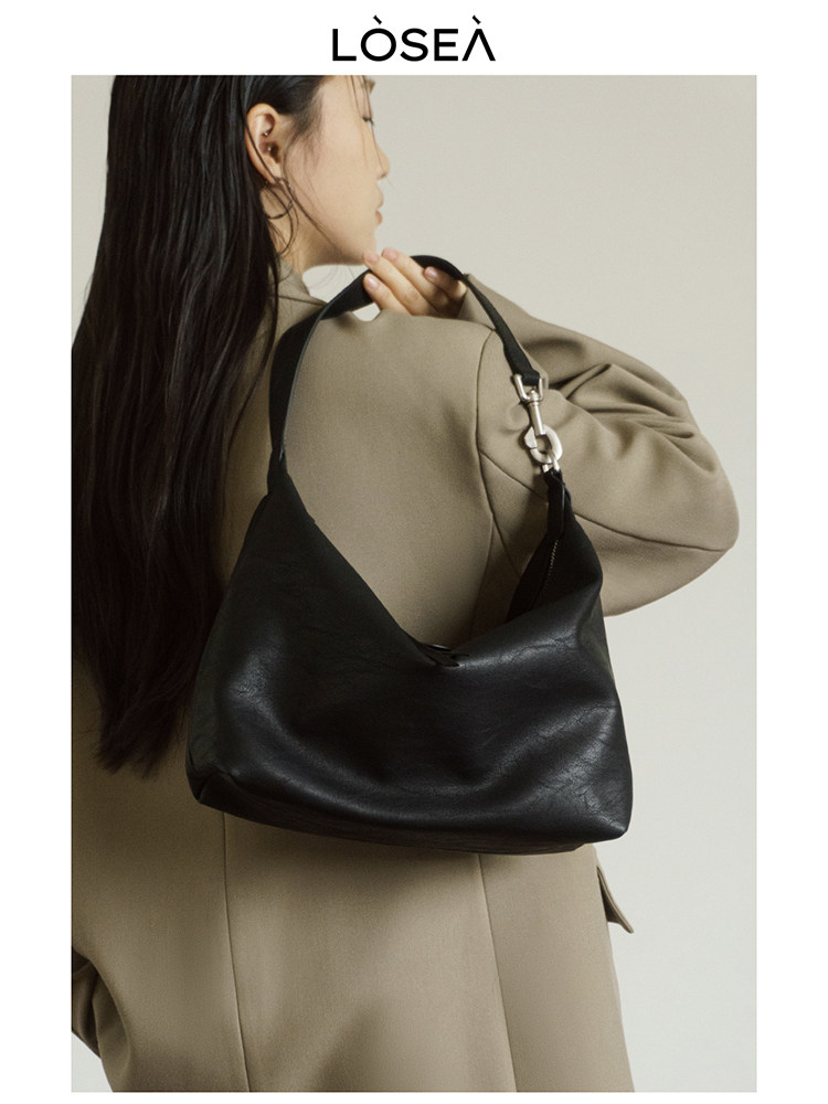 Black leather shoulder handbag worn by a model