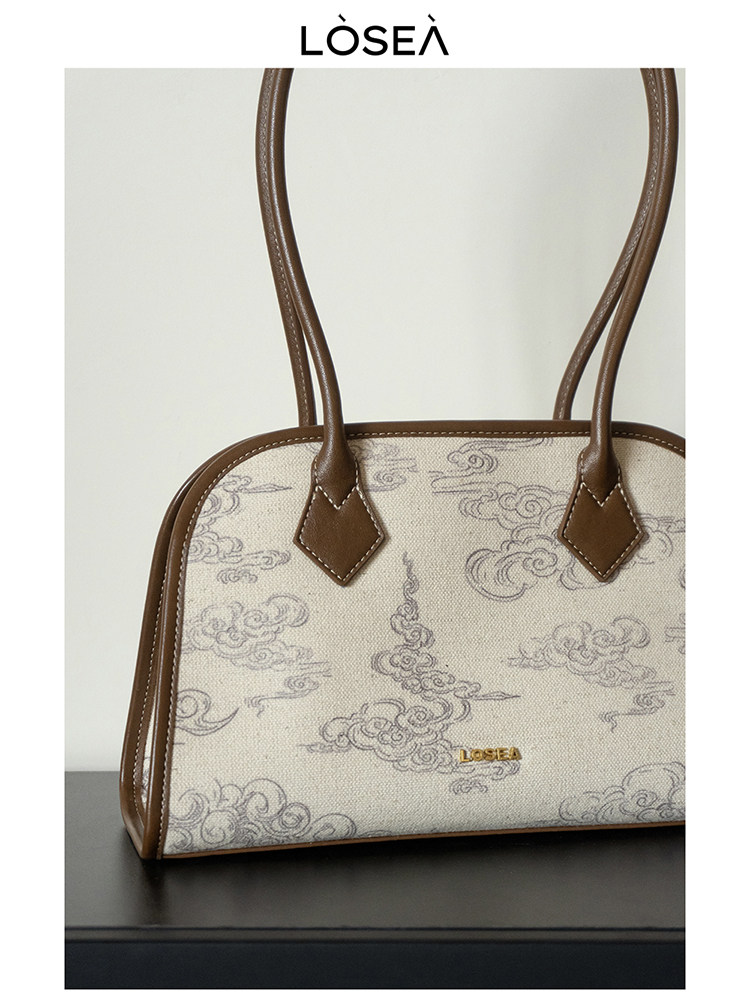 Beige patterned tote handbag with brown leather trim and handles