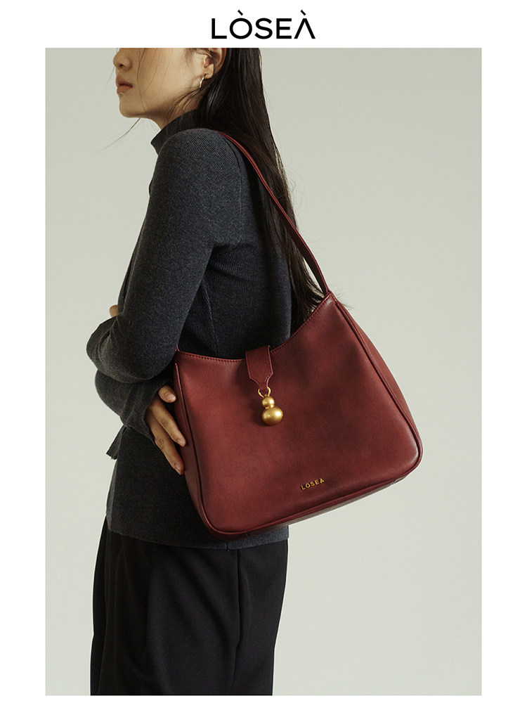 Red leather shoulder handbag worn on a model