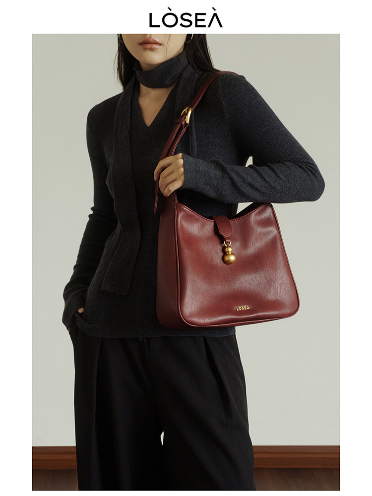 Model wearing a burgundy leather shoulder handbag
