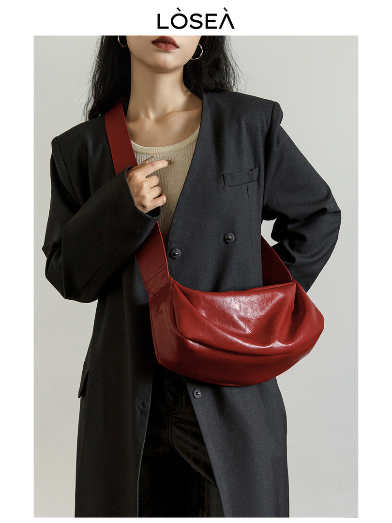 Model wearing a black blazer with a red shoulder bag