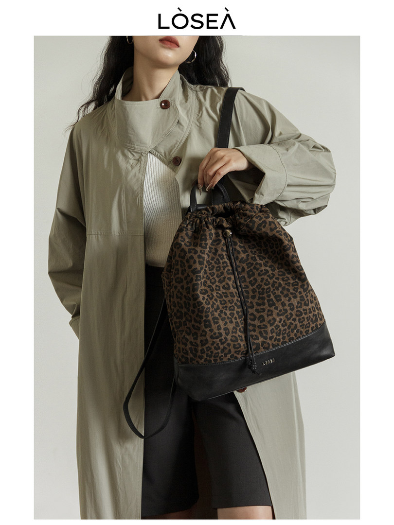 Leopard print drawstring backpack worn by a model with a trench coat